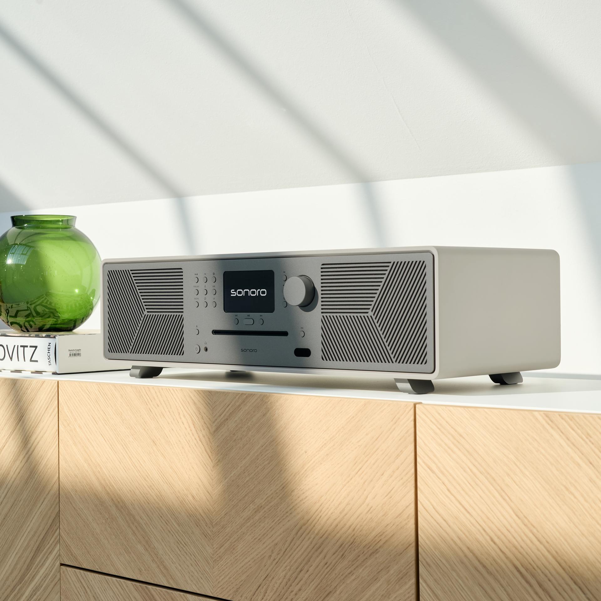 sonoro MEISTERSTÜCK Gen.2 in Weiß auf hellholzfarbenem Möbelstück – preisgekröntes HiFi-Design mit perfektem Klang fürs Wohnzimmer.